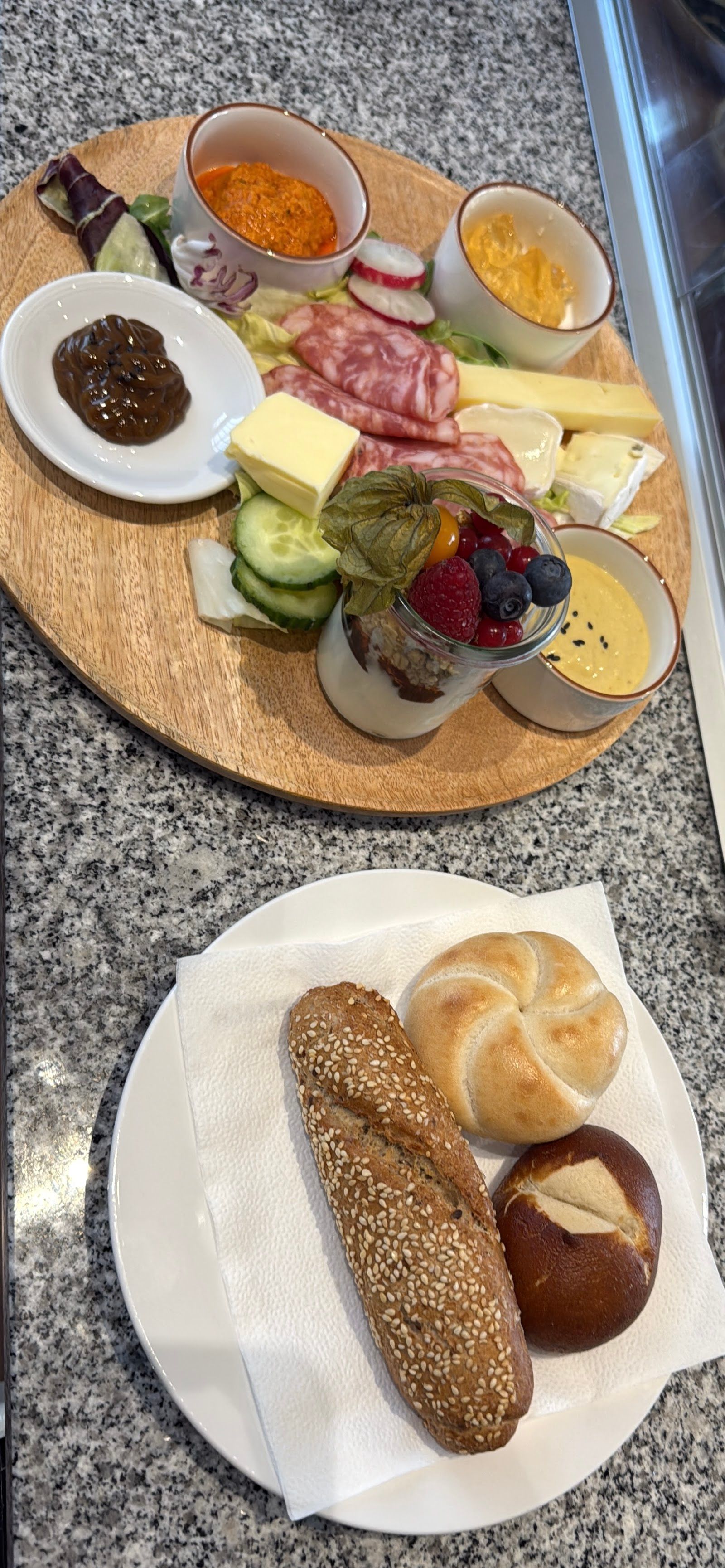 Reich belegtes Brunch-Board mit Aufschnitt, Käse, Dips und Brötchen von oben fotografiert.