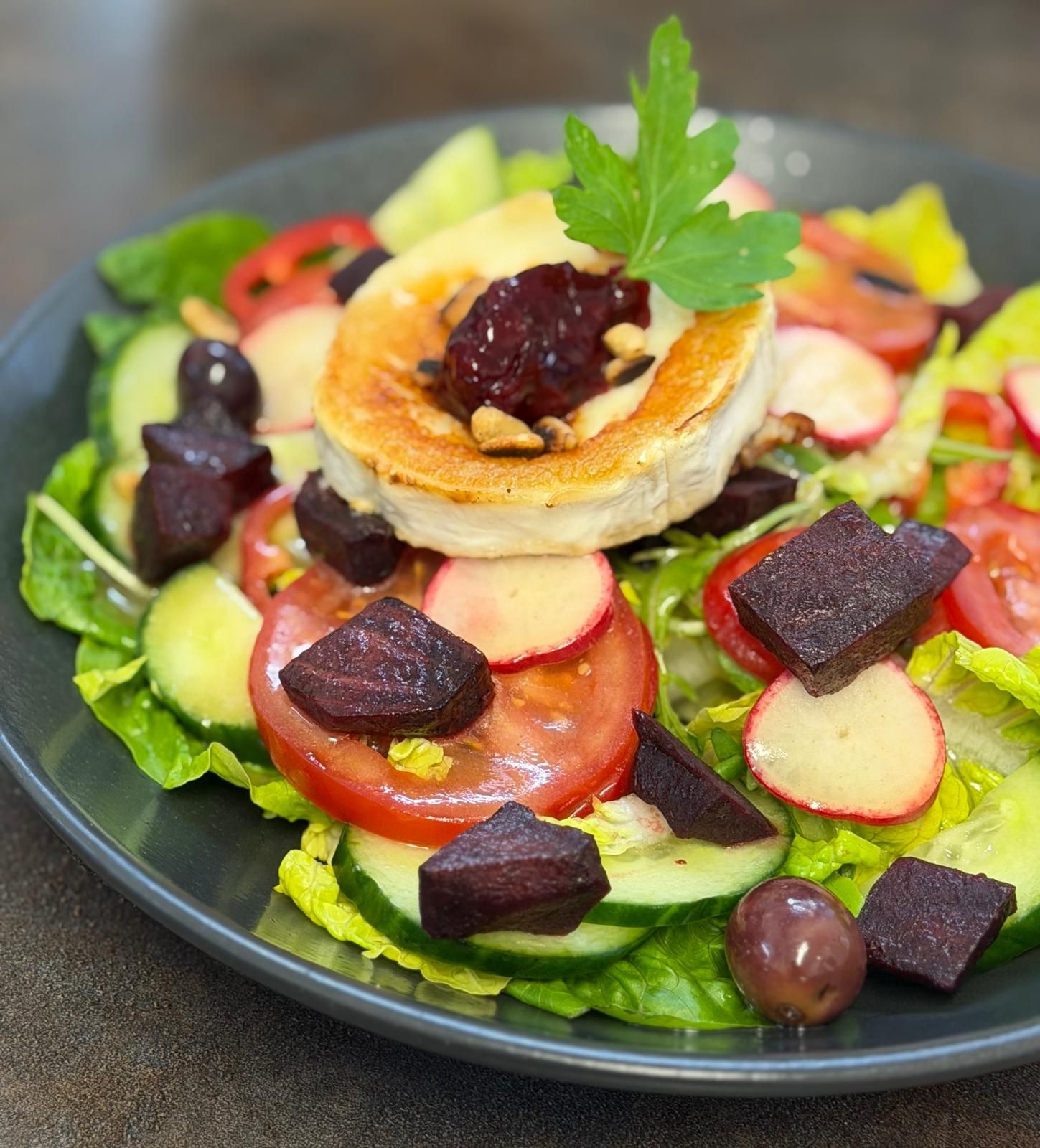 Gebackener Ziegenkäse auf frischem Salat mit Tomate, Bete und Oliven.
